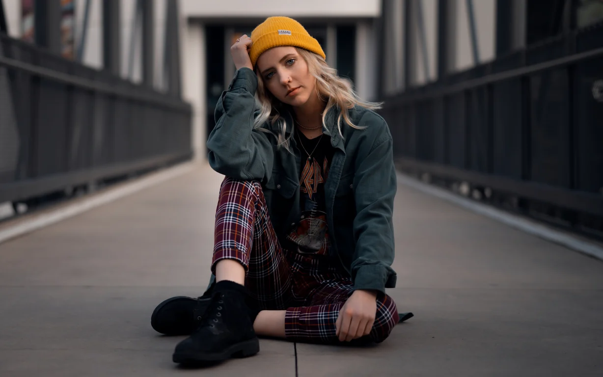 Christy seated at the center of a pedestrian bridge framed by converging railings